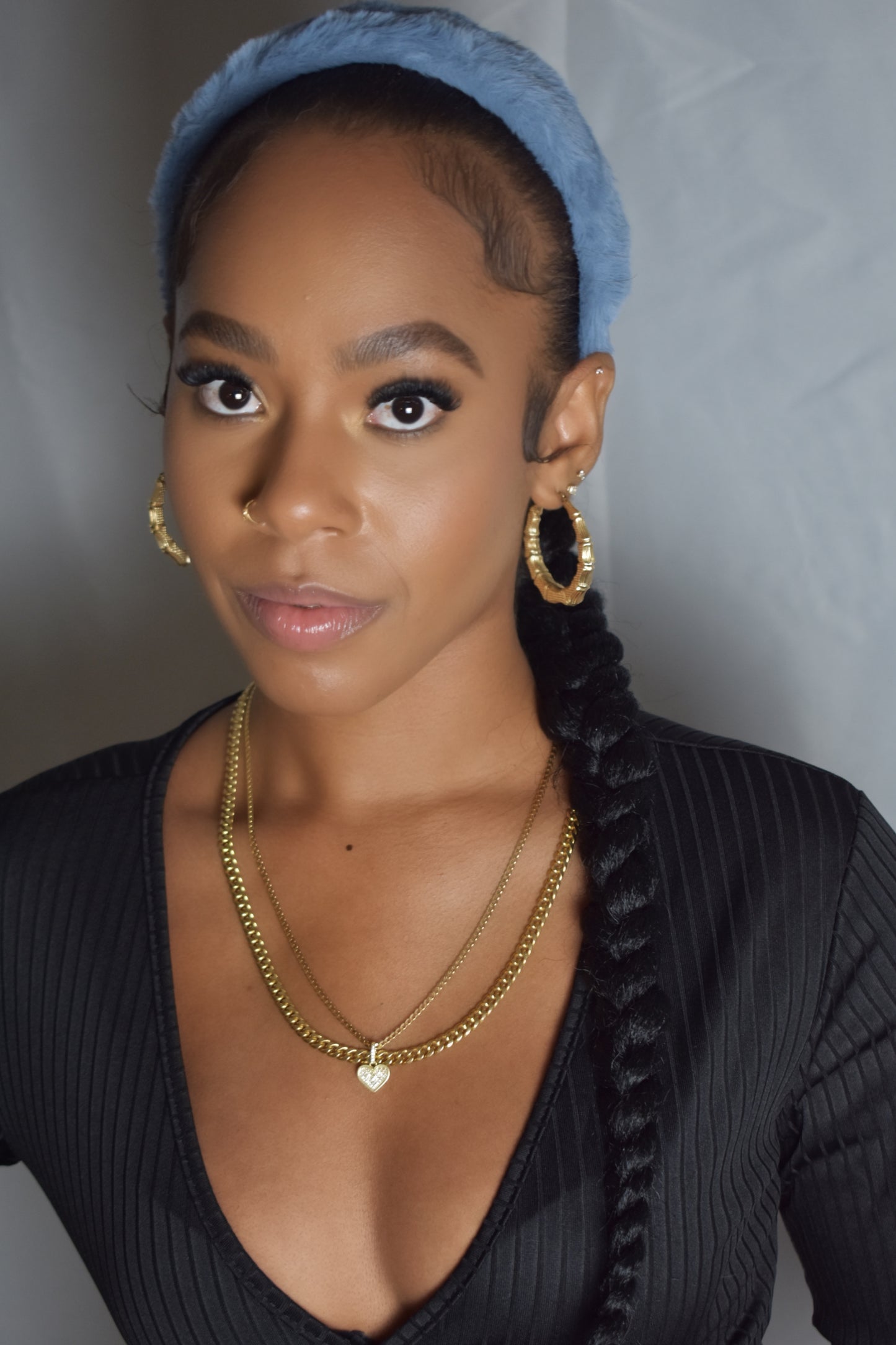 Woman with braided hair wearing a blue headband and gold jewelry. Snow Crown faux fur headband in soft plush material. Close-up of Snow Crown faux fur texture. Snow Crown faux fur headband styled as cute Y2K winter accessory. Snow Crown faux fur headband available in multiple colors.