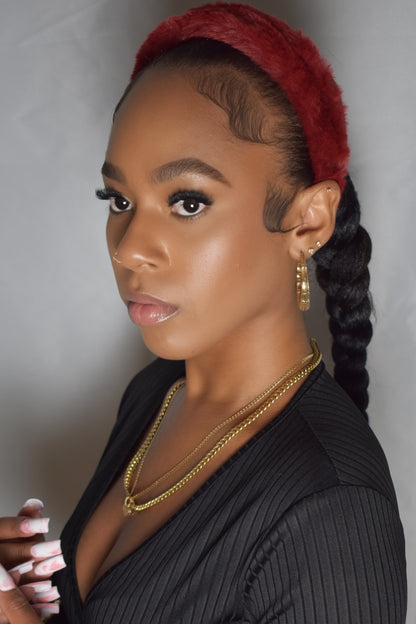 Woman with braided hair wearing a blue headband and gold jewelry. Snow Crown faux fur headband in soft plush material. Close-up of Snow Crown faux fur texture. Side view of furry Snow Crown headband with cozy fit. Snow Crown faux fur headband styled as cute Y2K winter accessory. Snow Crown faux fur headband available in multiple colors.