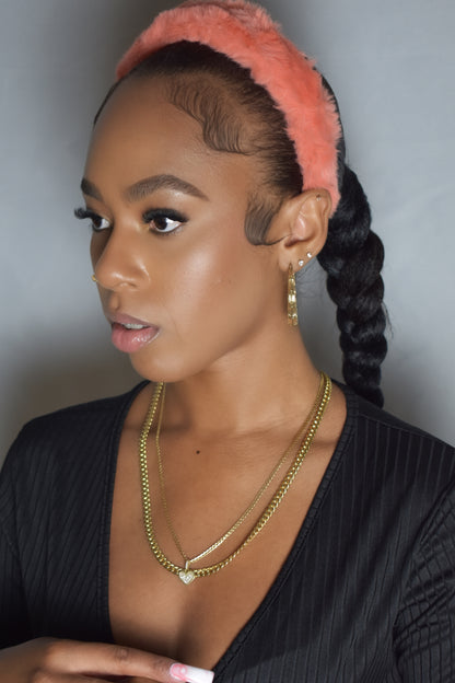 Woman with braided hair wearing a blue headband and gold jewelry. Snow Crown faux fur headband in soft plush material. Close-up of Snow Crown faux fur texture. Side view of furry Snow Crown headband with cozy fit. Snow Crown faux fur headband styled as cute Y2K winter accessory. Snow Crown faux fur headband available in multiple colors.