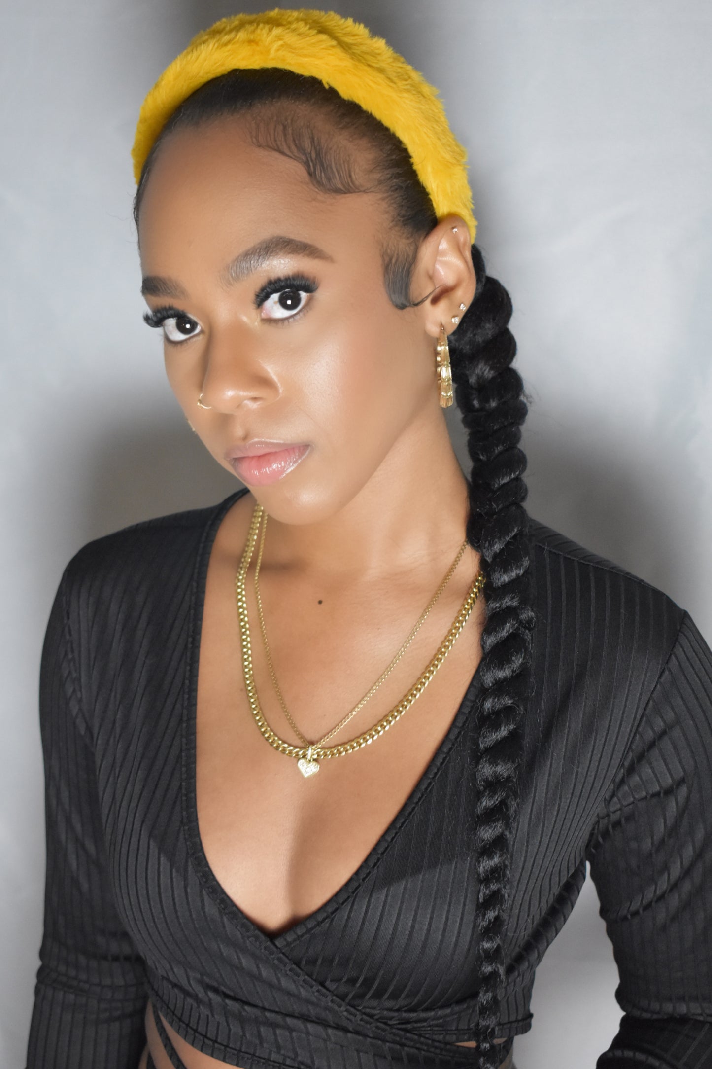 Woman with braided hair wearing a blue headband and gold jewelry. Snow Crown faux fur headband in soft plush material. Close-up of Snow Crown faux fur texture. Snow Crown faux fur headband styled as cute Y2K winter accessory. Snow Crown faux fur headband available in multiple colors.