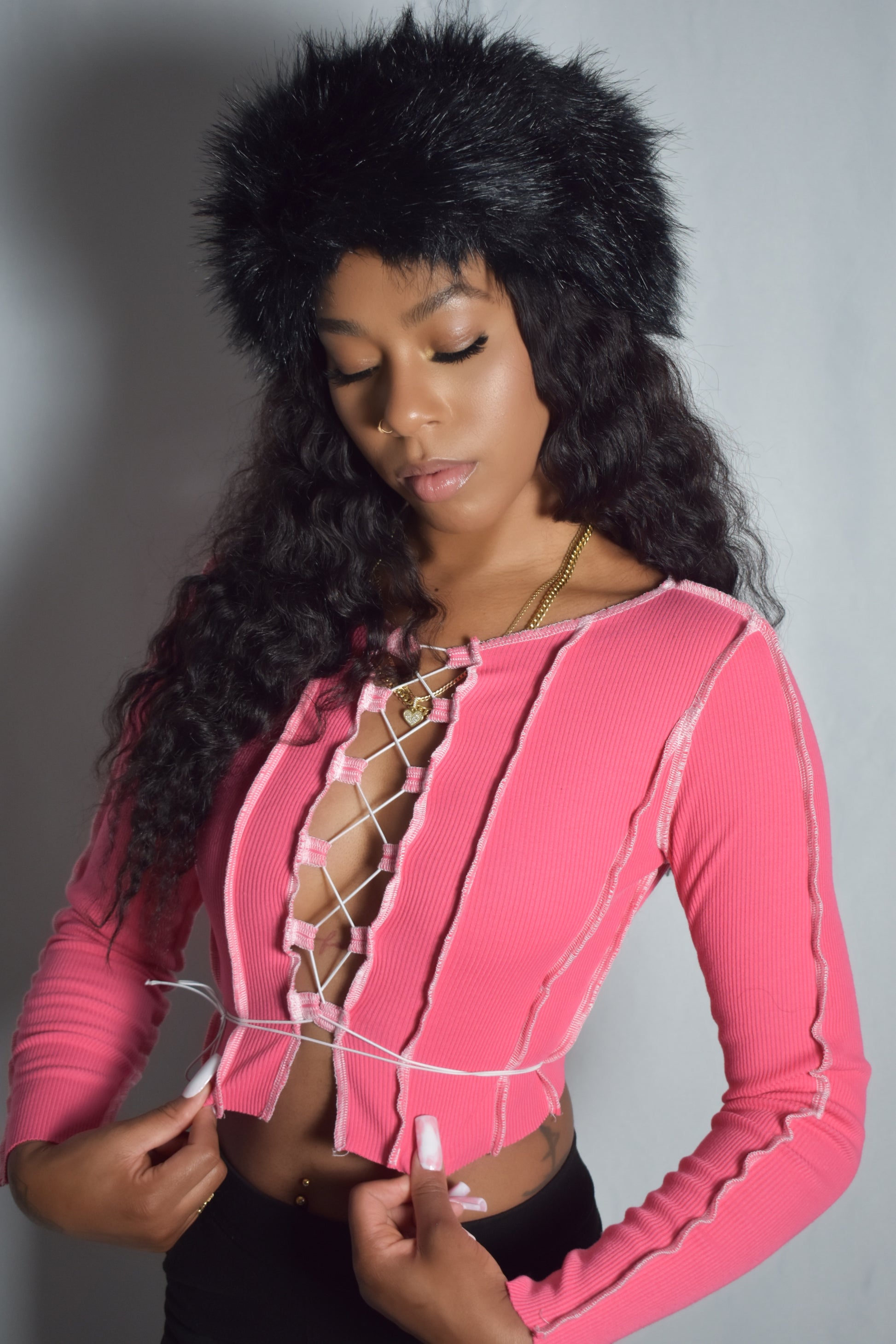 Long-sleeve lace-up crop top pink with adjustable string front in Y2K style, black stacked pants, black fur boots, black jumbo faux fur headband, stylish outfit