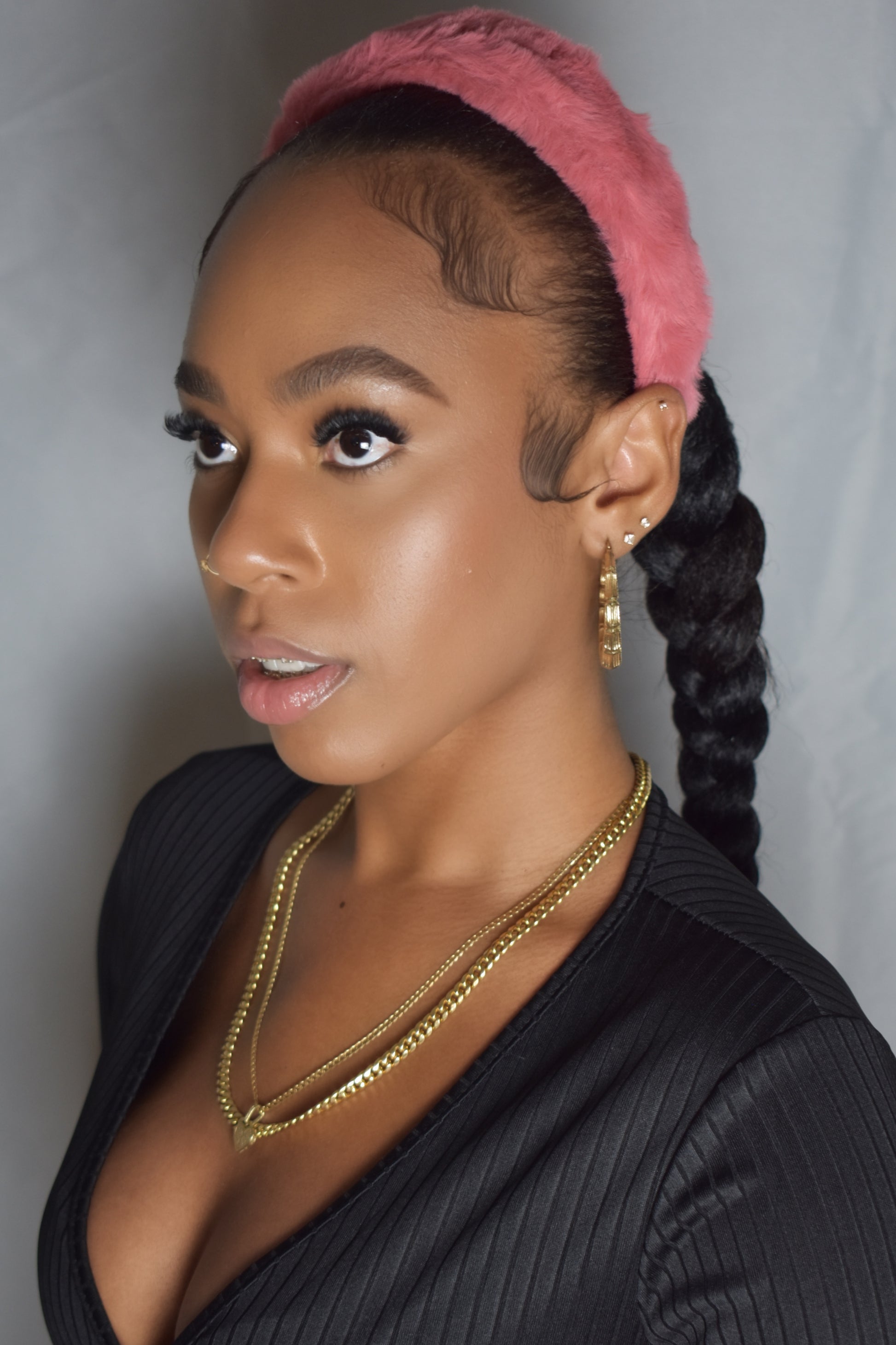 Woman with braided hair wearing a blue headband and gold jewelry. Snow Crown faux fur headband in soft plush material. Close-up of Snow Crown faux fur texture. Side view of furry Snow Crown headband with cozy fit. Snow Crown faux fur headband styled as cute Y2K winter accessory. Snow Crown faux fur headband available in multiple colors.