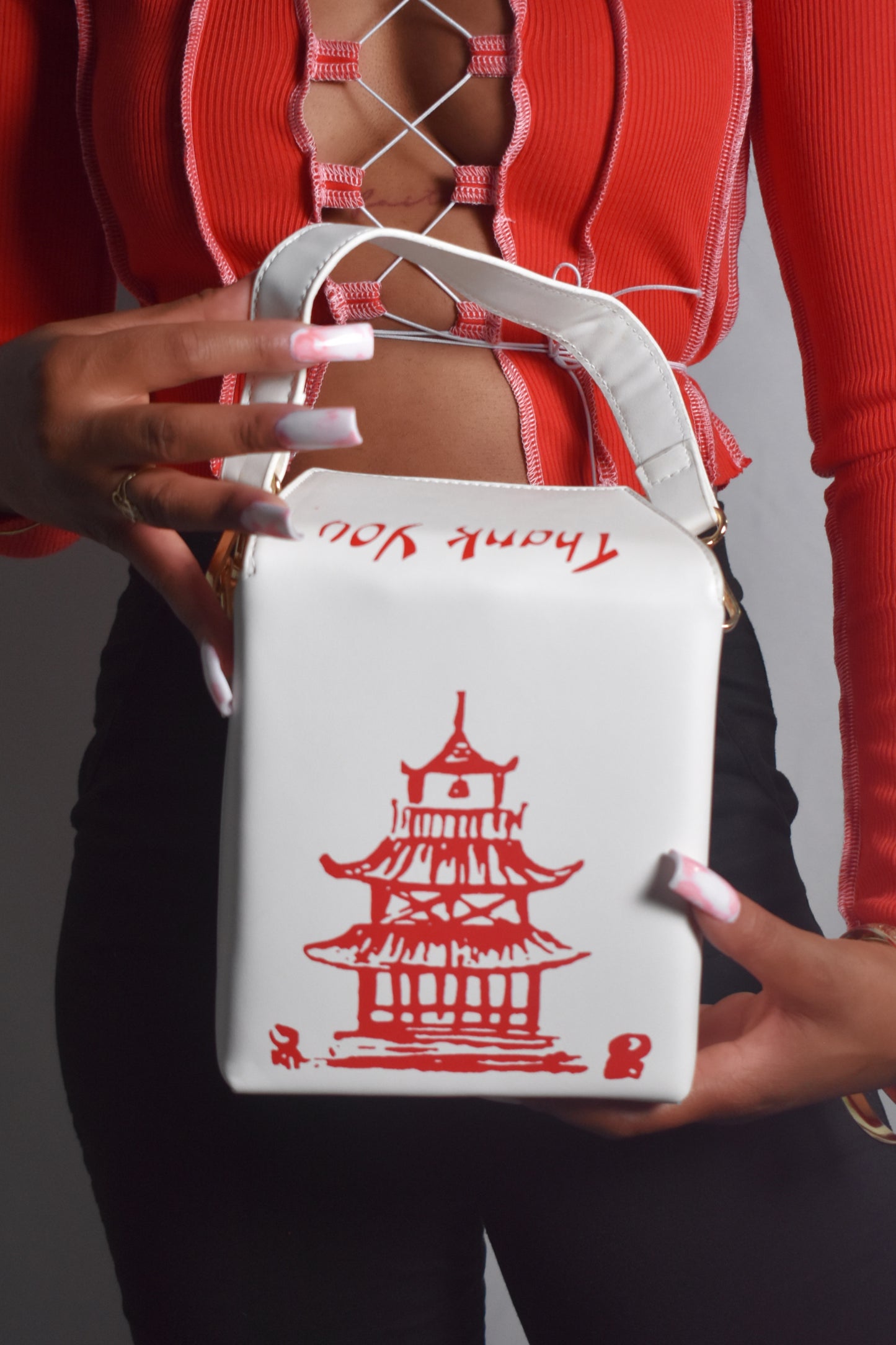 White bag with red pagoda design held by a person wearing a red outfit. Kawaii Kiss Asian takeout-style bag with tower illustration and ‘Thank You’ text.
