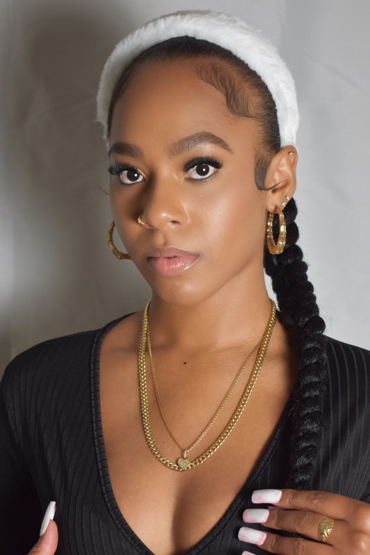 Woman with braided hair wearing a blue headband and gold jewelry. Snow Crown faux fur headband in soft plush material. Close-up of Snow Crown faux fur texture. Snow Crown faux fur headband styled as cute Y2K winter accessory. Snow Crown faux fur headband available in multiple colors.